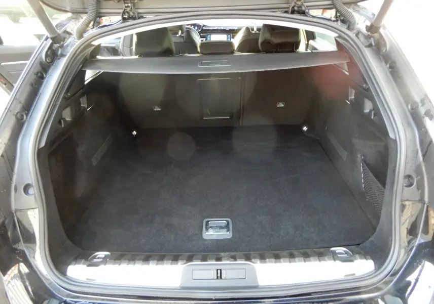 Coffre ouvert en vue arrière d'une Peugeot 508 SW noire, montrant un espace de chargement spacieux et propre.