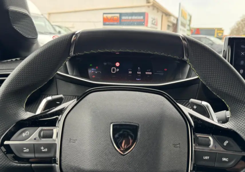 Vue rapprochée du volant cuir noir et du tableau de bord numérique de la Peugeot 208 Hybrid 110 e-DCS6 GT 2025.