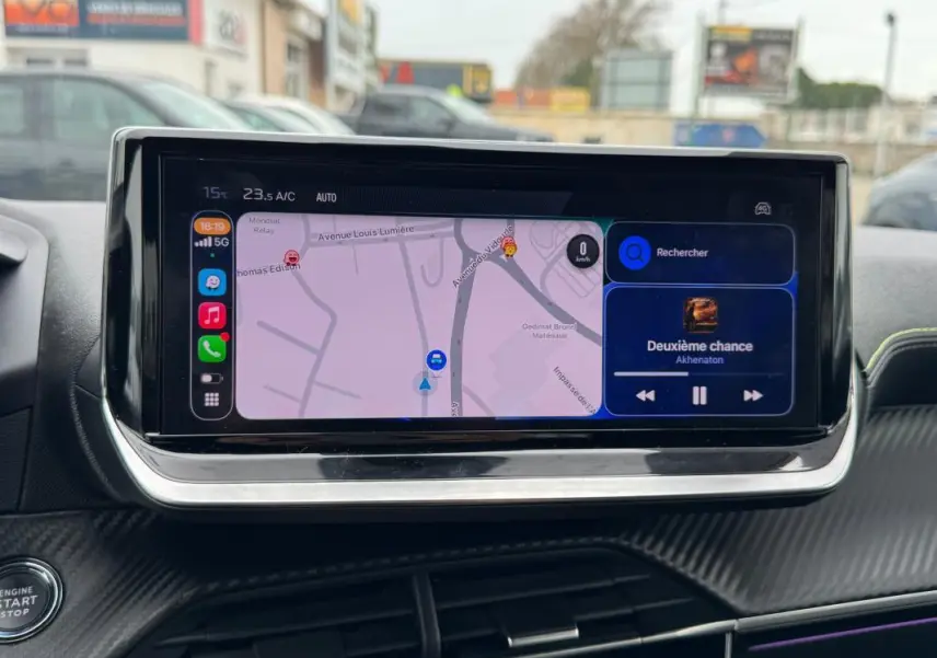 Vue rapprochée de l’écran tactile central du Peugeot 208 gris, affichant la navigation et la musique en cours.