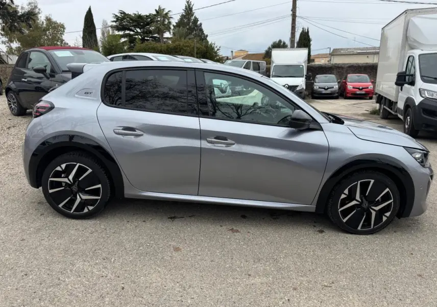 Vue de profil côté gauche d'une Peugeot 208 Hybrid 110 GT gris métallisé avec jantes alliage 17 pouces et vitres teintées.