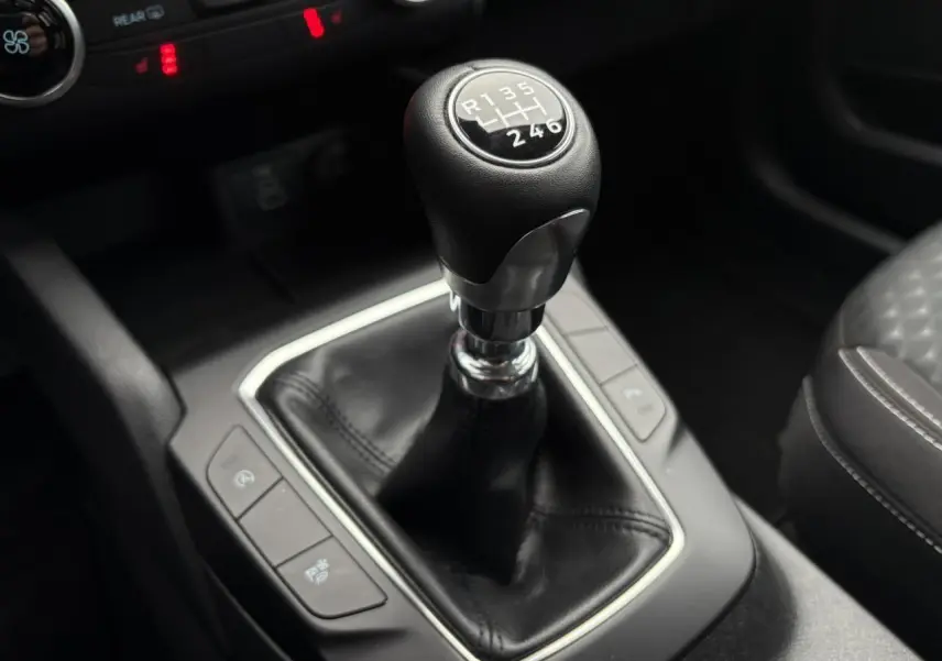 Gros plan sur le levier de vitesses manuel du Ford Kuga 2024, entouré de commandes et sellerie noire.