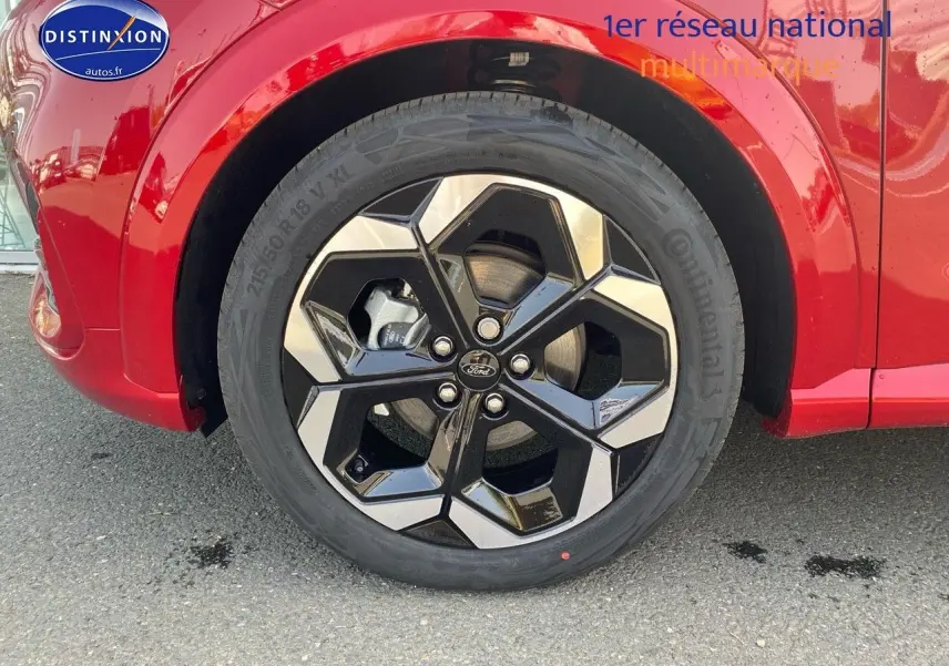 Gros plan sur la roue avant gauche avec jante alu noire et argent sur Ford Puma rouge métallisé.