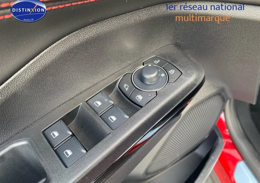 Vue rapprochée des commandes des vitres et rétroviseurs sur la porte avant gauche d’un Ford Puma rouge métallisé.