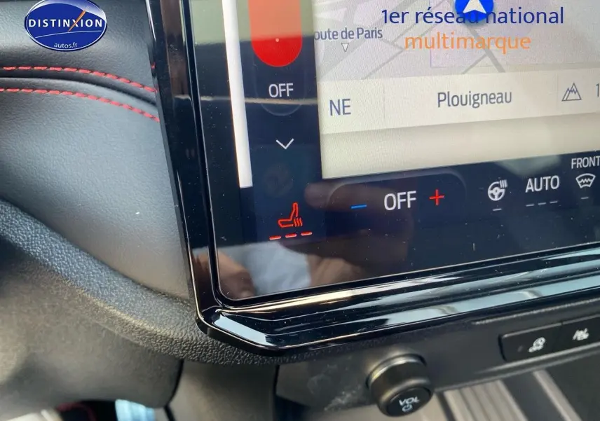 Détail de l'écran tactile central avec commandes de climatisation et surpiqûres rouges sur tableau de bord noir du Ford Puma rouge.