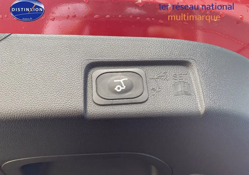 Gros plan sur le bouton d'ouverture électrique du coffre sur la partie intérieure rouge métallisée du Ford Puma 2026.