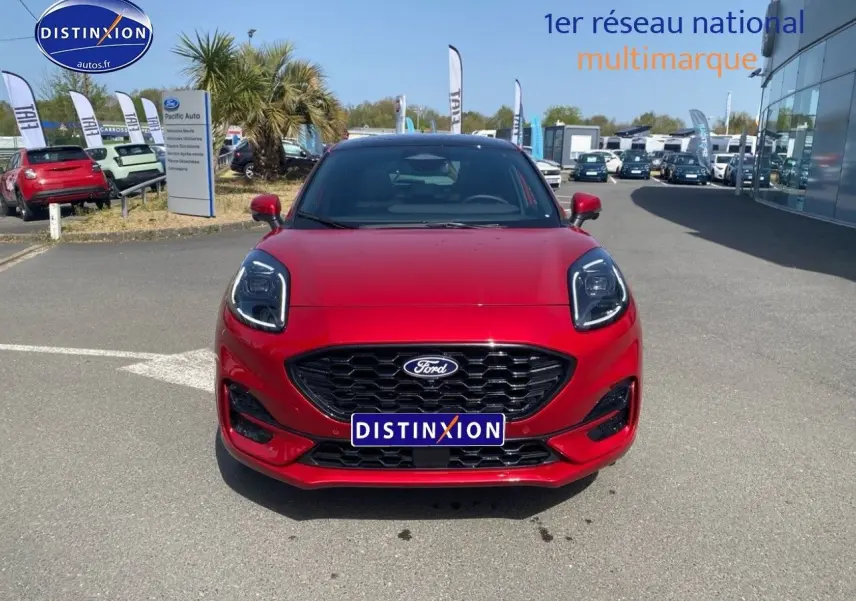 Vue frontale d'une Ford Puma rouge métallisée avec calandre noire et phares LED marqués, sur parking extérieur.