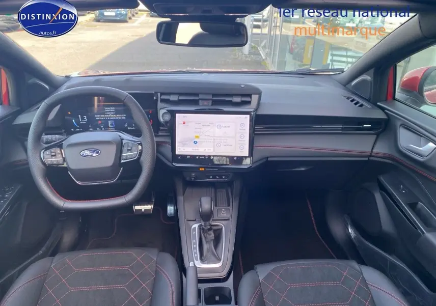Vue intérieure avant du Ford Puma rouge avec volant multifonction, écran tactile central et surpiqûres rouges sur les sièges sport.