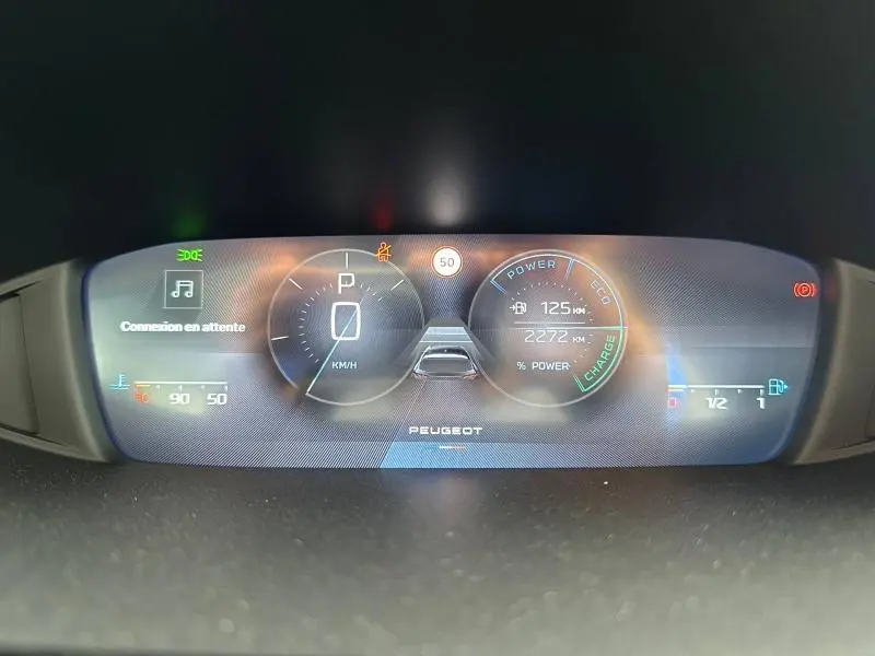 Tableau de bord numérique de Peugeot 308 Hybrid 2025 affichant vitesse, autonomie et indicateurs de charge en vue frontale.
