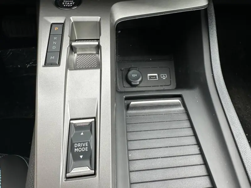 Vue rapprochée de la console centrale gris clair de la Peugeot 308 Hybrid avec sélecteur de boîte auto et prises USB et 12V.