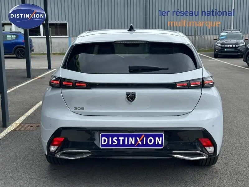 Vue arrière d'une Peugeot 308 blanche Okénite avec feux arrière LED et double sortie d'échappement chromée.