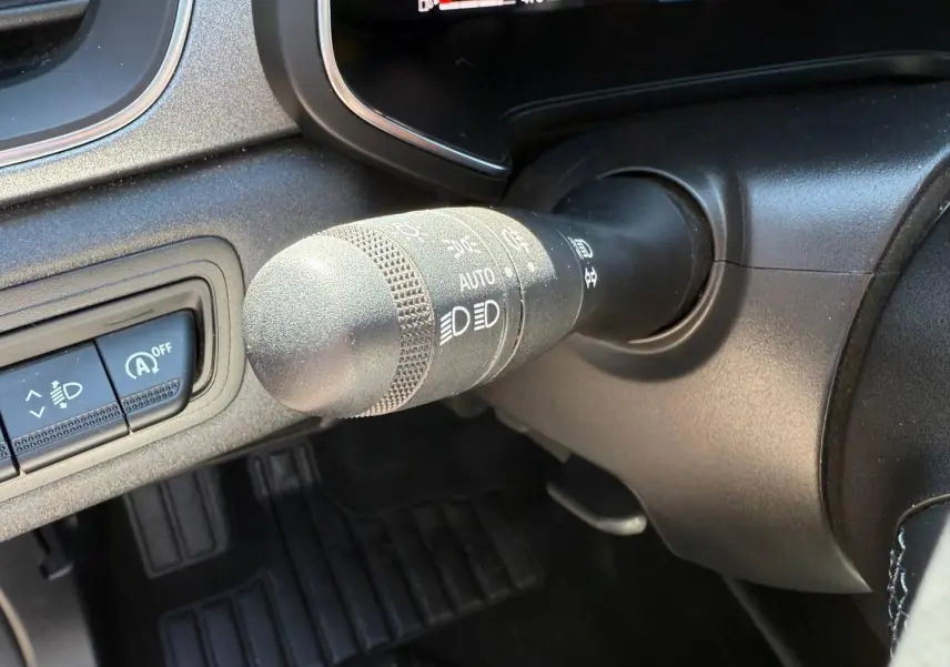 Gros plan sur la commande des phares et essuie-glaces dans l'habitacle noir du Renault Captur 2025.