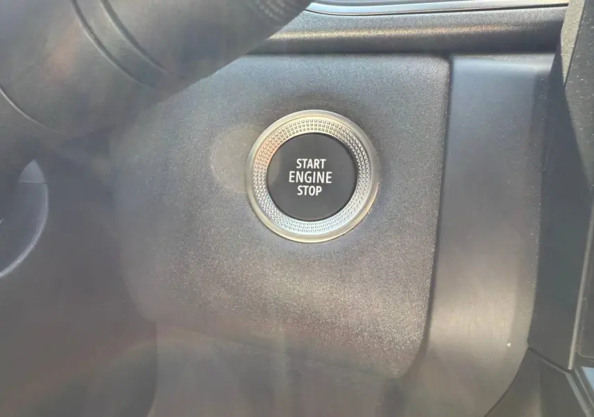 Gros plan sur le bouton Start Engine Stop noir entouré d'un anneau argenté dans l'habitacle du Renault Captur 2025.
