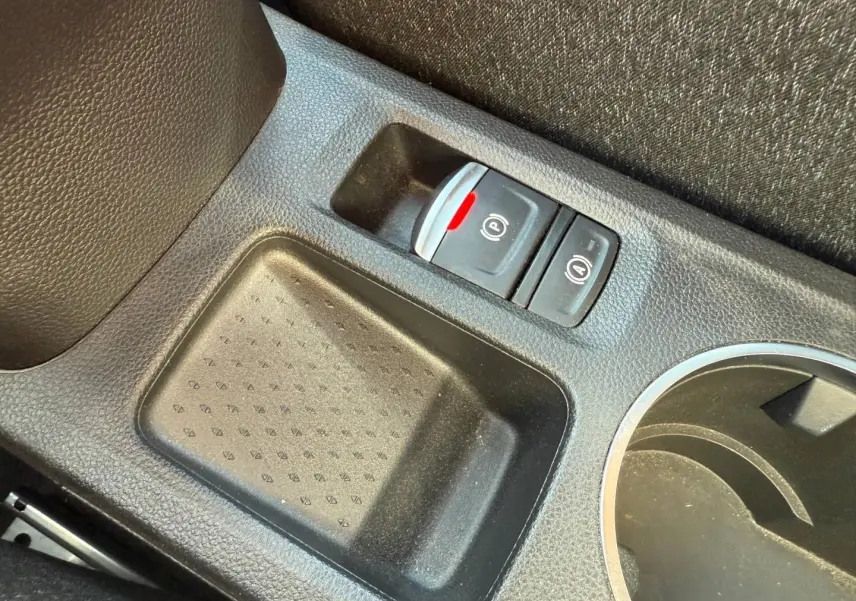Gros plan sur la console centrale noire du Renault Captur 2025, avec bouton frein à main électrique et porte-gobelets.