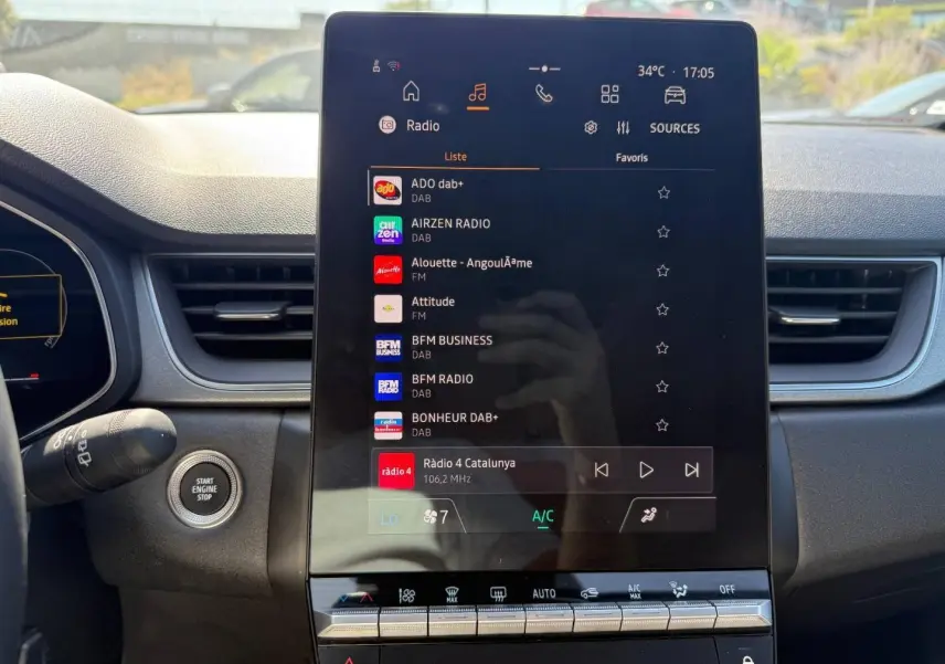 Écran tactile central du tableau de bord du Renault Captur 2025, affichant les options radio et climatisation.