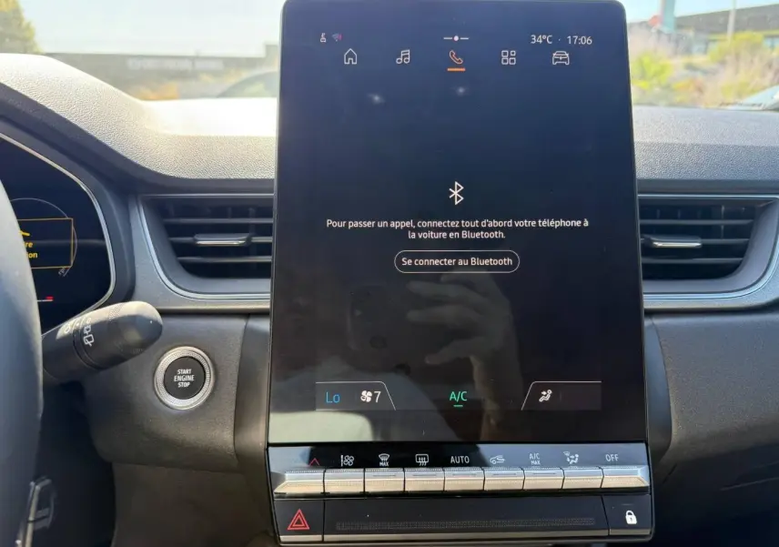 Vue rapprochée de l’écran tactile central et du bouton start/stop du tableau de bord du Renault Captur gris métallisé 2025.
