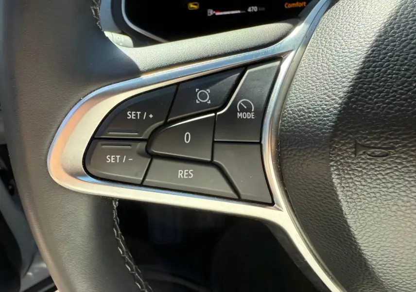 Gros plan sur les commandes multifonctions à gauche du volant noir du Renault Captur 2025, boutons de régulateur de vitesse.