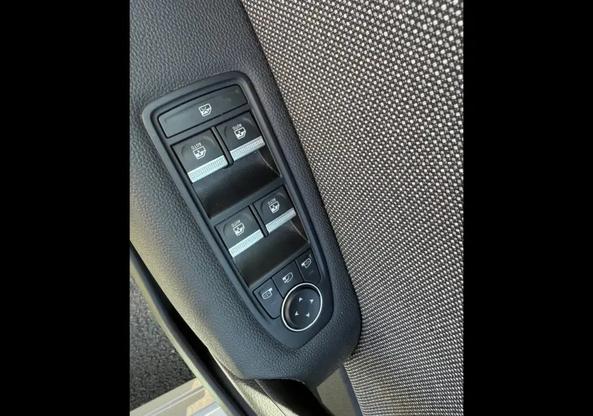 Panneau de commandes des vitres électriques et rétroviseurs sur la porte avant gauche d'un Renault Captur gris.