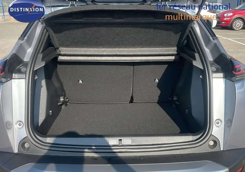 Coffre ouvert d'un Peugeot 2008 gris Artense métal, vue arrière montrant l'espace de chargement vide et la plage arrière relevée.