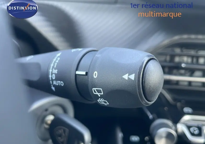 Gros plan sur la commande d'essuie-glace du Peugeot 2008 gris Artense, avec tableau de bord flou en arrière-plan.