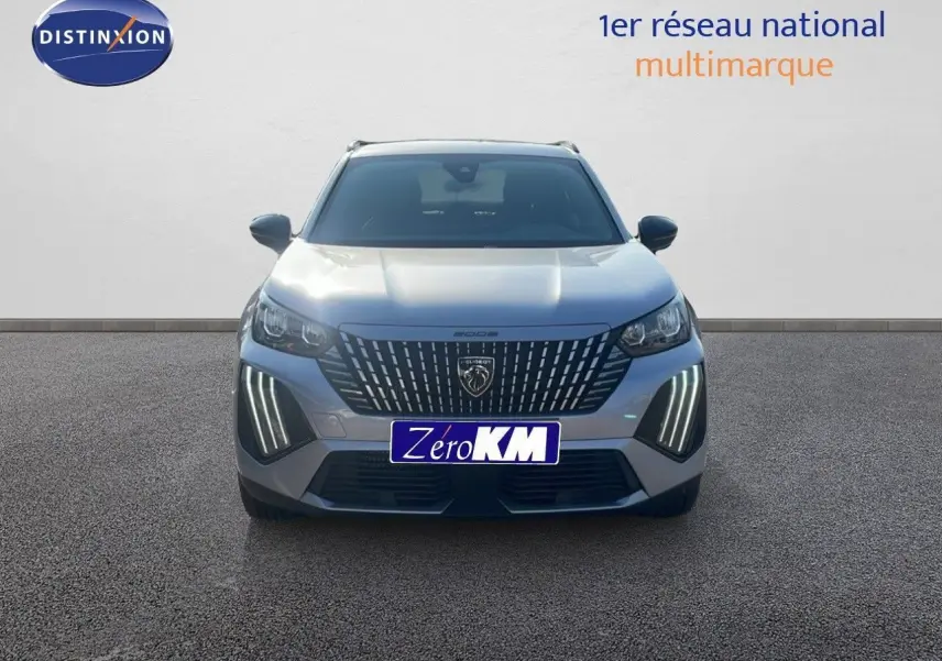 Vue frontale d'un Peugeot 2008 Hybrid 136ch gris Artense métal avec ses phares LED verticaux allumés.