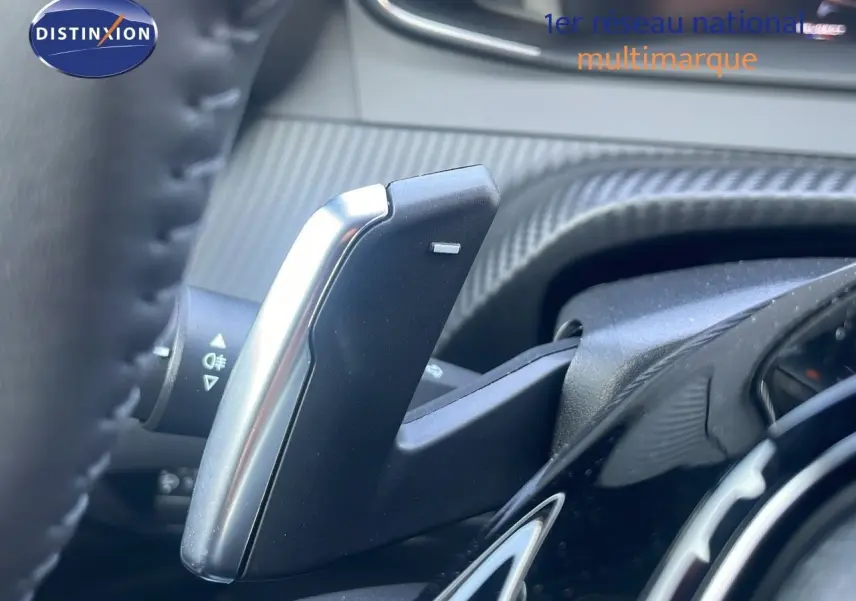 Gros plan sur la palette de changement de vitesse du Peugeot 2008 Hybrid gris Artense, avec tableau de bord en arrière-plan.