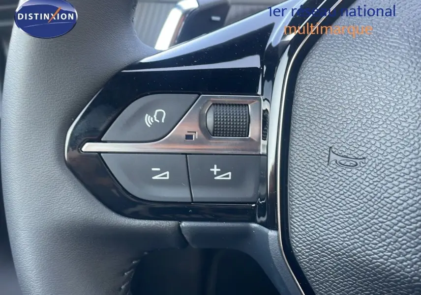 Gros plan sur les commandes gauche du volant noir du Peugeot 2008 Hybrid gris Artense 2025, avec boutons de volume et appel.