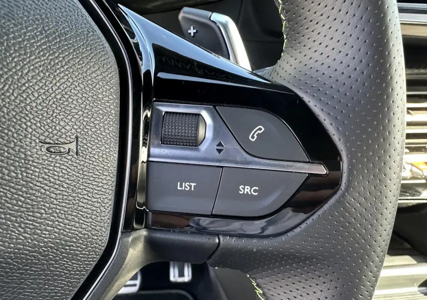Gros plan sur les commandes gauche du volant cuir perforé gris du Peugeot 208 Hybrid 145 e-DSC6 GT 2024.