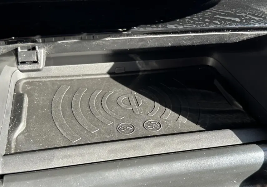 Gros plan sur le tapis de recharge sans fil Qi noir dans la console centrale de la Peugeot 208 Hybrid 145 e-DSC6 GT 2024.