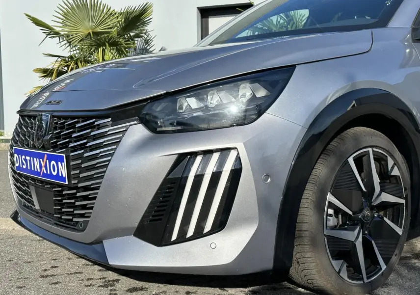 Vue 3/4 avant droit d'une Peugeot 208 Hybrid 145 gris Artense avec calandre noire et jantes alliage diamantées.
