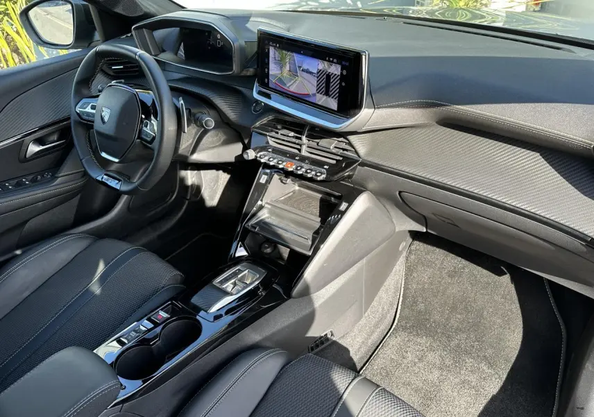 Vue intérieure côté conducteur de la Peugeot 208 Hybrid 145 GT avec écran tactile 10 pouces et sellerie noire.