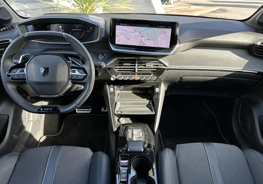 Intérieur Peugeot 208 Hybrid 145 GT vu de face, tableau de bord noir avec écran tactile GPS 10 pouces et volant compact cuir.