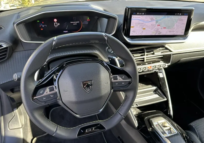 Intérieur du Peugeot 208 Hybrid 145 GT montrant le volant cuir GT et l'écran tactile GPS 10 pouces en vue avant centrale.