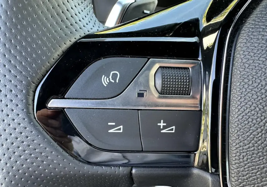 Gros plan sur les commandes vocales et volume du volant cuir perforé du Peugeot 208 Hybrid 145 e-DSC6 GT 2024.