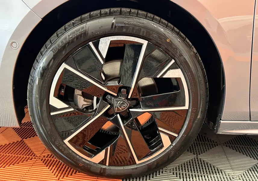 Gros plan sur la jante noire et argentée du côté gauche d'une Peugeot 508 SW gris artense 2024.