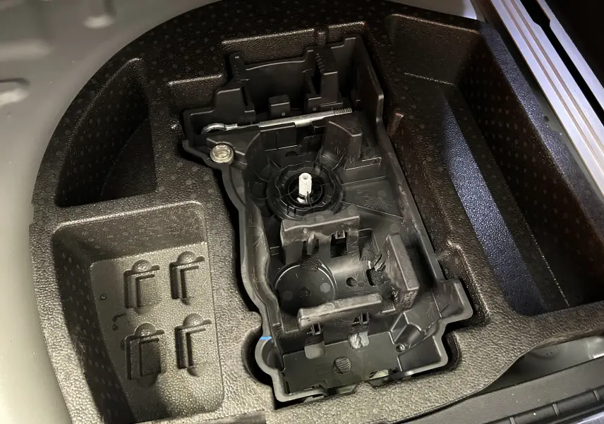 Gros plan sur le rangement en mousse du coffre d'une Peugeot 508 SW gris artense, montrant un support d'outils intégré.