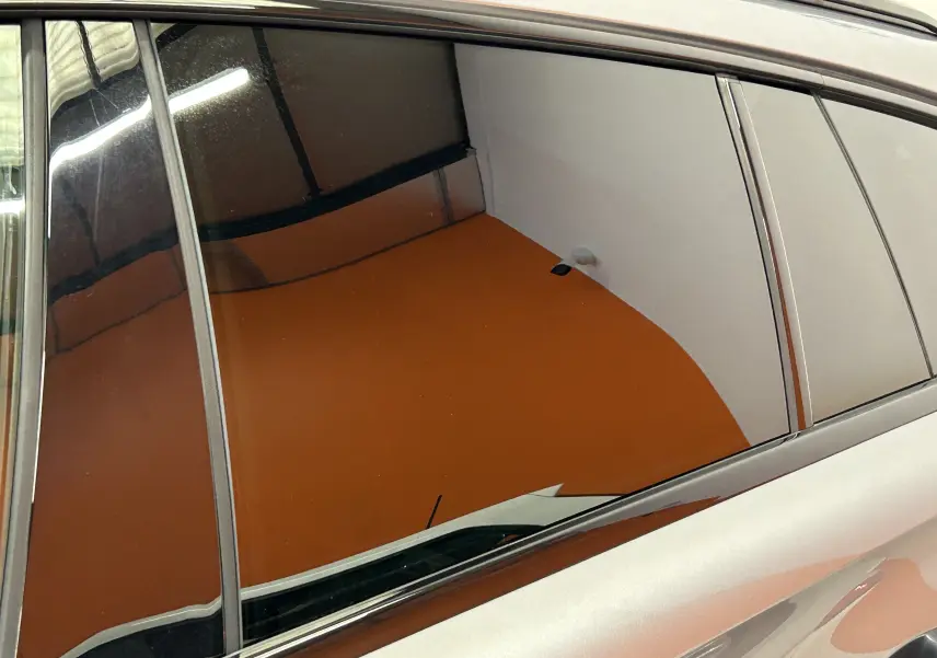 Reflet sur la vitre arrière côté gauche d'une Peugeot 508 SW gris artense, montrant la carrosserie lisse et brillante.