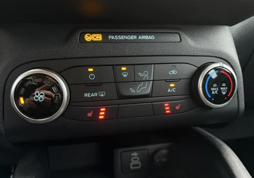 Panneau de commande de climatisation avec sièges chauffants activés sur Ford Kuga noir Obsidien, vue intérieure rapprochée.