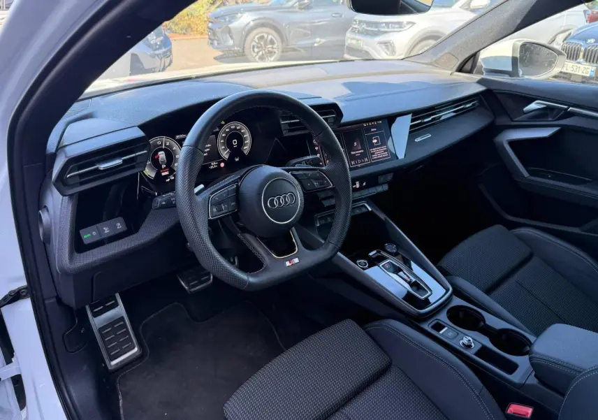 Vue intérieure côté conducteur de l'Audi A3 Sportback blanc Glacier, volant sport et tableau de bord numérique.