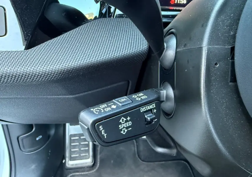 Gros plan sur la commande de régulateur de vitesse au volant d’un Audi A3 Sportback blanc Glacier 2025.
