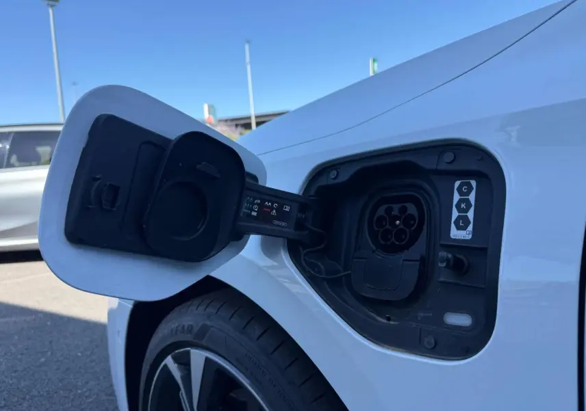 Prise de recharge ouverte côté arrière droit d’une Audi A3 Sportback blanche Glacier métallisé, jante alu visible.