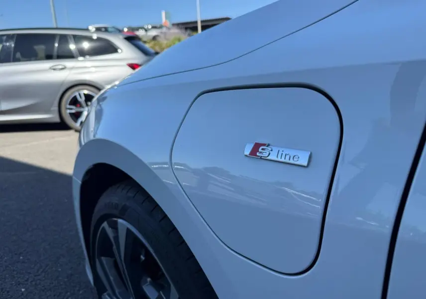 Gros plan sur l'aile avant gauche blanche Glacier métallisé d'une Audi A3 Sportback 2025 avec logo S line.