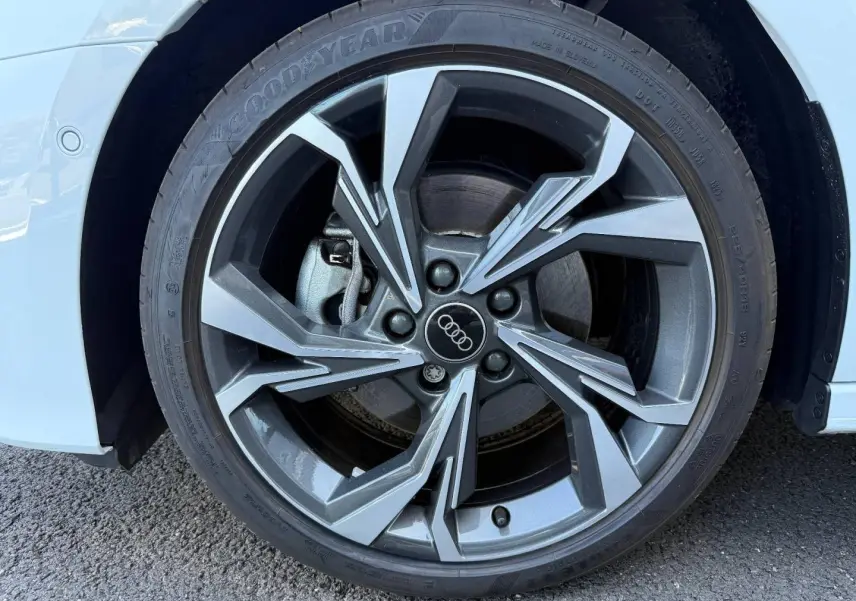 Gros plan sur la jante alu grise à design géométrique de l'Audi A3 Sportback blanc Glacier métallisé, côté avant droit.