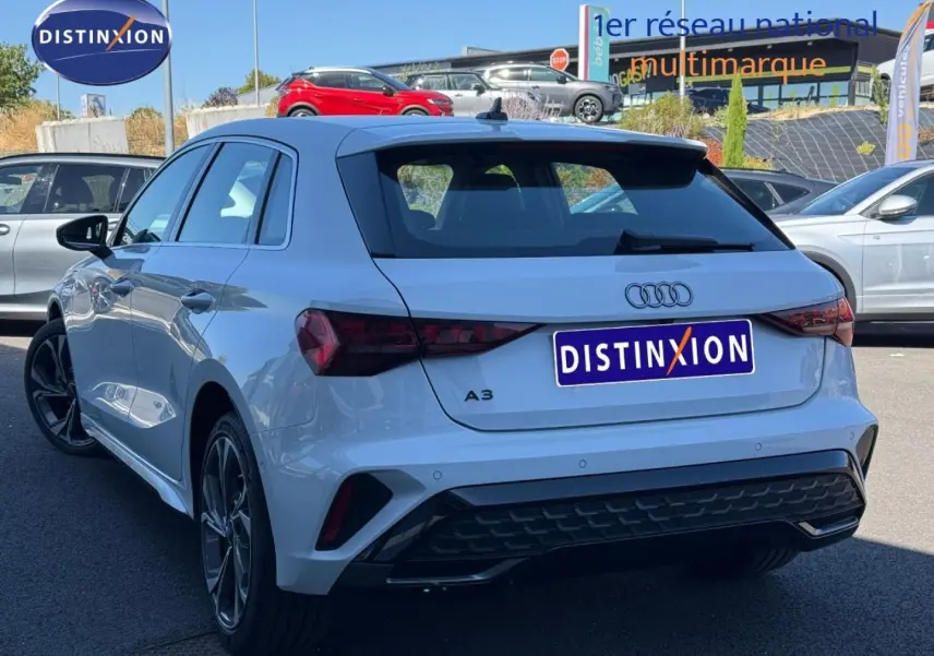 Audi A3 Sportback blanc Glacier métallisé vue 3/4 arrière droit, avec jantes alu et becquet arrière noir.