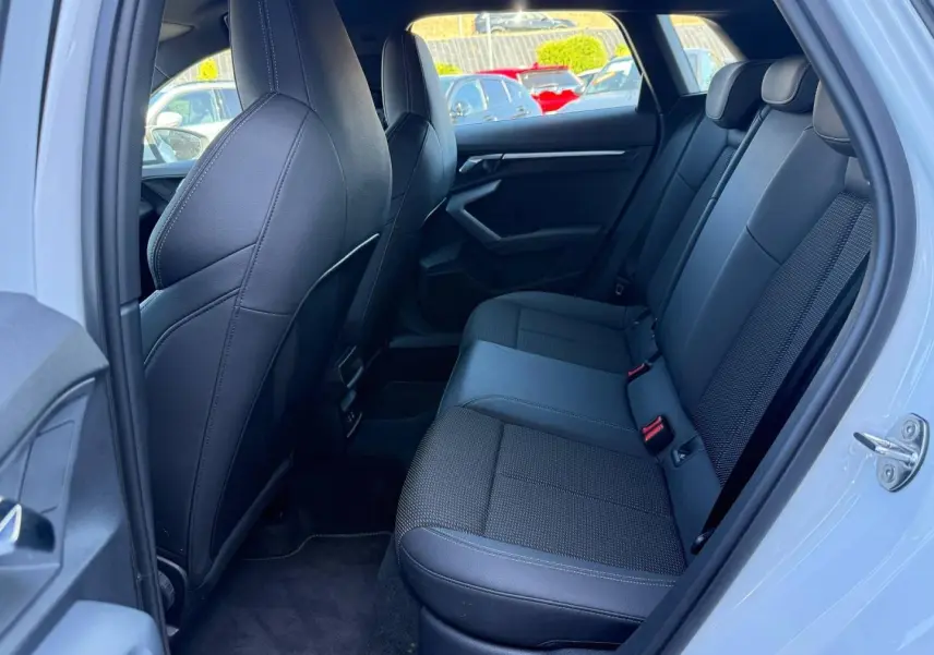 Vue intérieure côté droit sur la banquette arrière noire en tissu et simili de l'Audi A3 Sportback Blanc Glacier 2025.