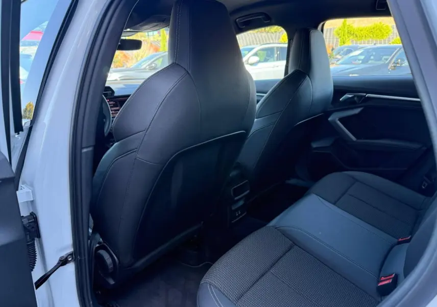 Vue intérieure arrière côté gauche de l’Audi A3 Sportback 2025 blanc Glacier, sièges sport noirs en tissu et simili.