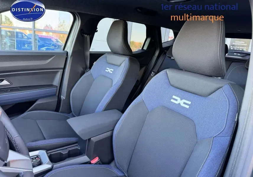 Vue intérieure côté gauche montrant les sièges avant bleu et noir avec logo Dacia sur un Dacia Duster 2025.