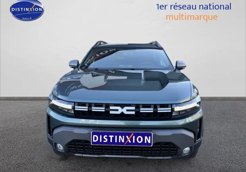 Vue avant d'un Dacia Duster 2025 vert cèdre avec calandre noire et phares LED allumés.