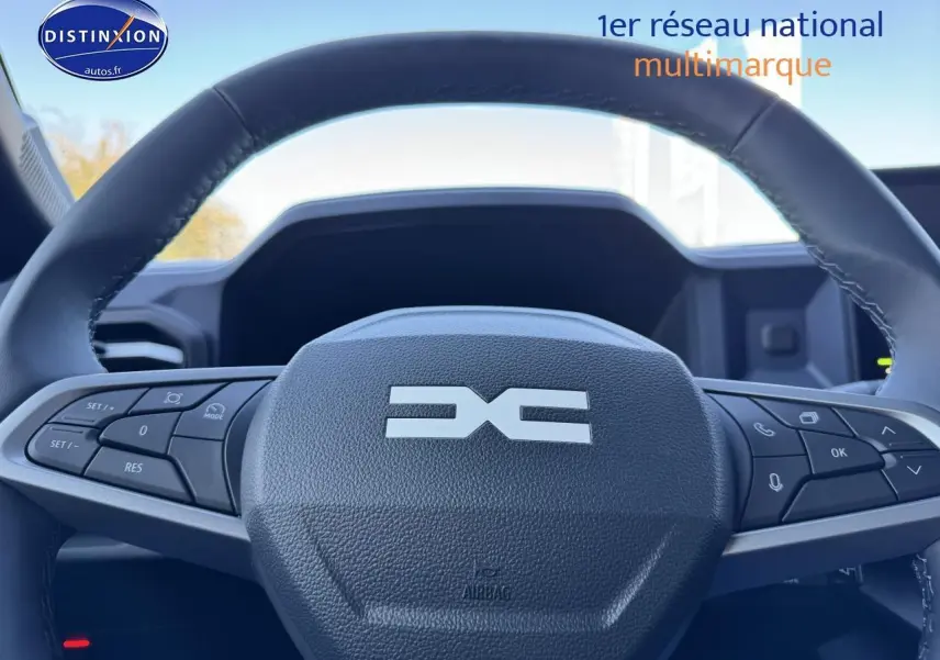 Gros plan sur le volant multifonction noir du Dacia Duster 2025, avec commandes intégrées visibles.