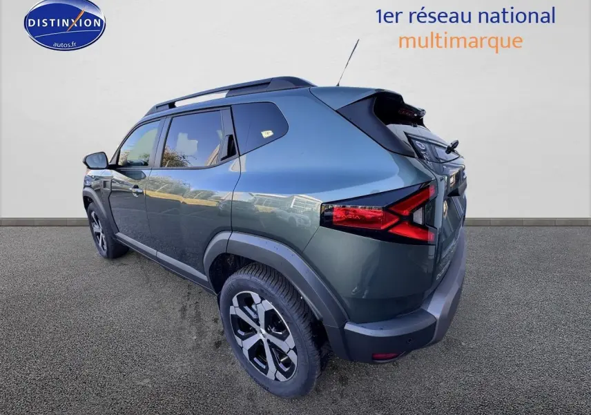 Vue 3/4 arrière droite du Dacia Duster 2025 vert cèdre avec barres de toit et jantes alu noires.