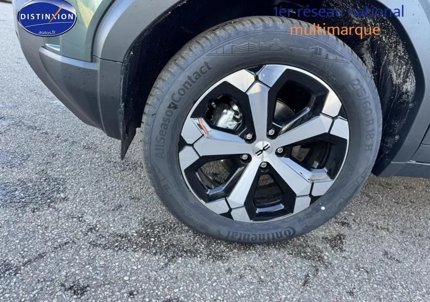 Gros plan sur la roue avant droite du Dacia Duster vert cèdre, jante alu bicolore et pneu Continental.